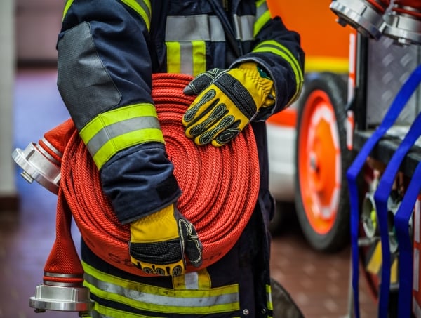 A firefighter carries a hose and nozzle