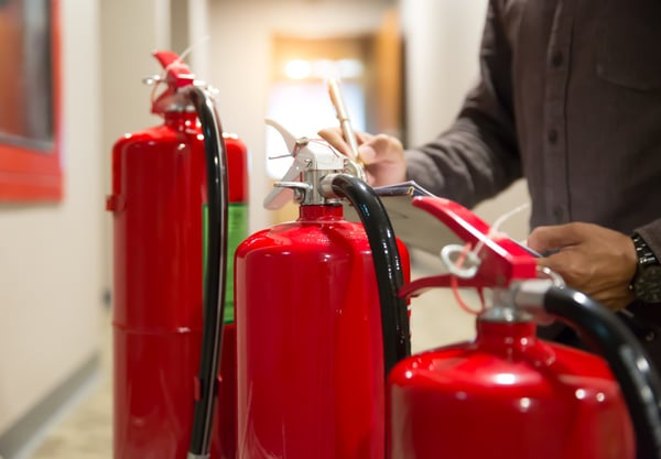 A person checks fire extinguishers for recent inspection and maintenance