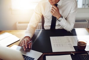 Man in white shirt workin at his desk and using his laptop computer