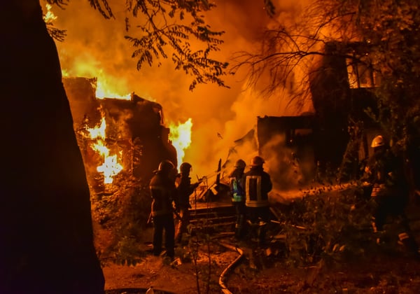 Firefighters fighting a wildfire burning a home