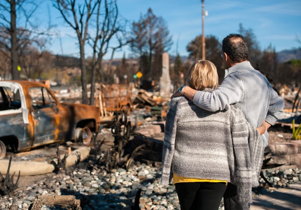 A couple surveys homes burned by a wildfire