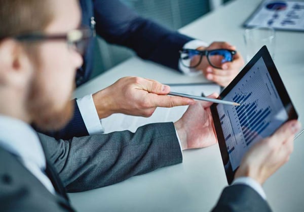 Two people analyzing data displayed on a tablet for a Loss Cost update