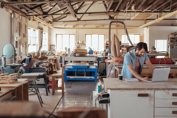 man stands at his desk inside of a craftsman workshop